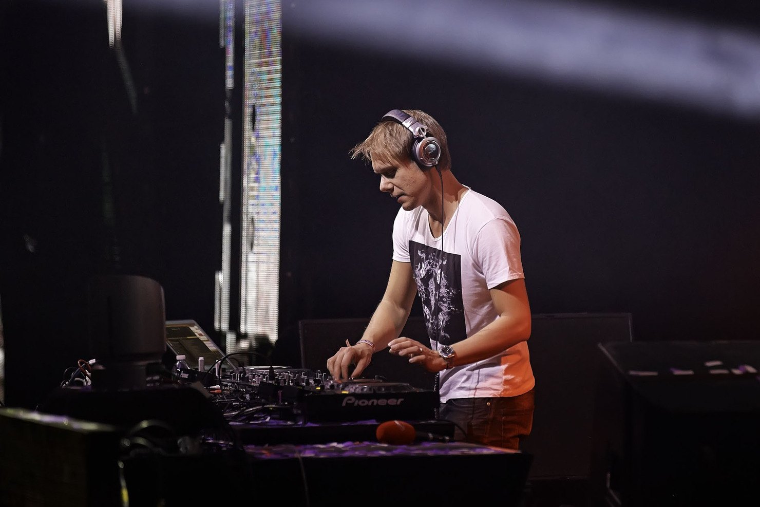 Armin van Buuren in headphones at the decks on a dark stage at Madison Square Garden, 2013