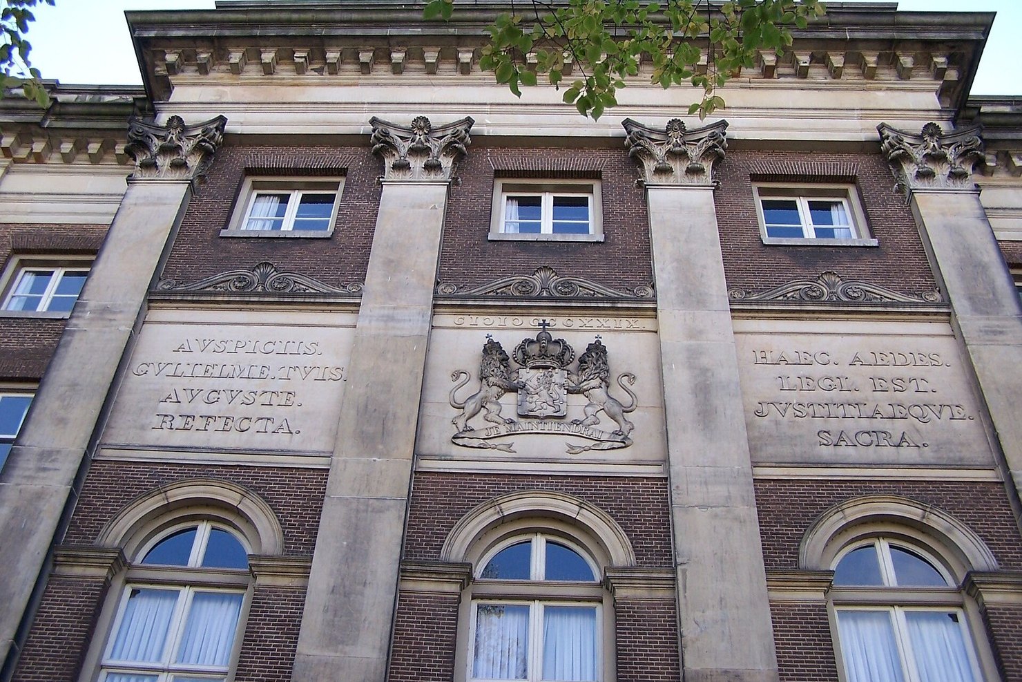 Stone and brick facade of the former Palace of Justice at Prinsengracht 436 in Amsterdam, with a carved coat of arms and Latin inscriptions above arched windows