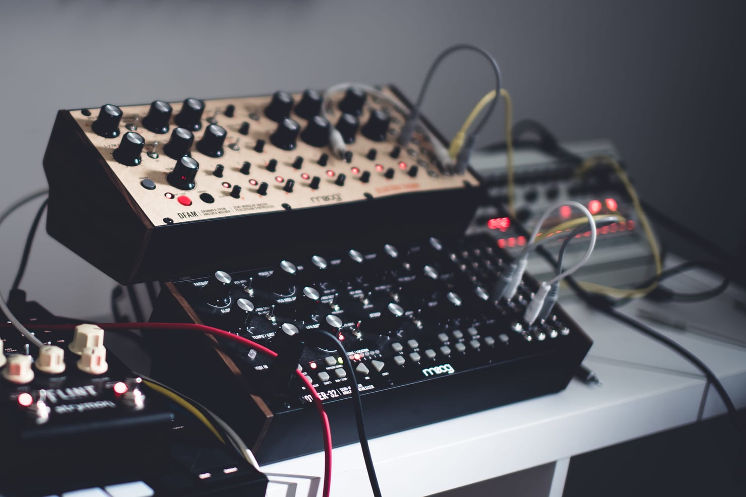 A Moog semi-modular synthesiser patched with cables on a studio desk