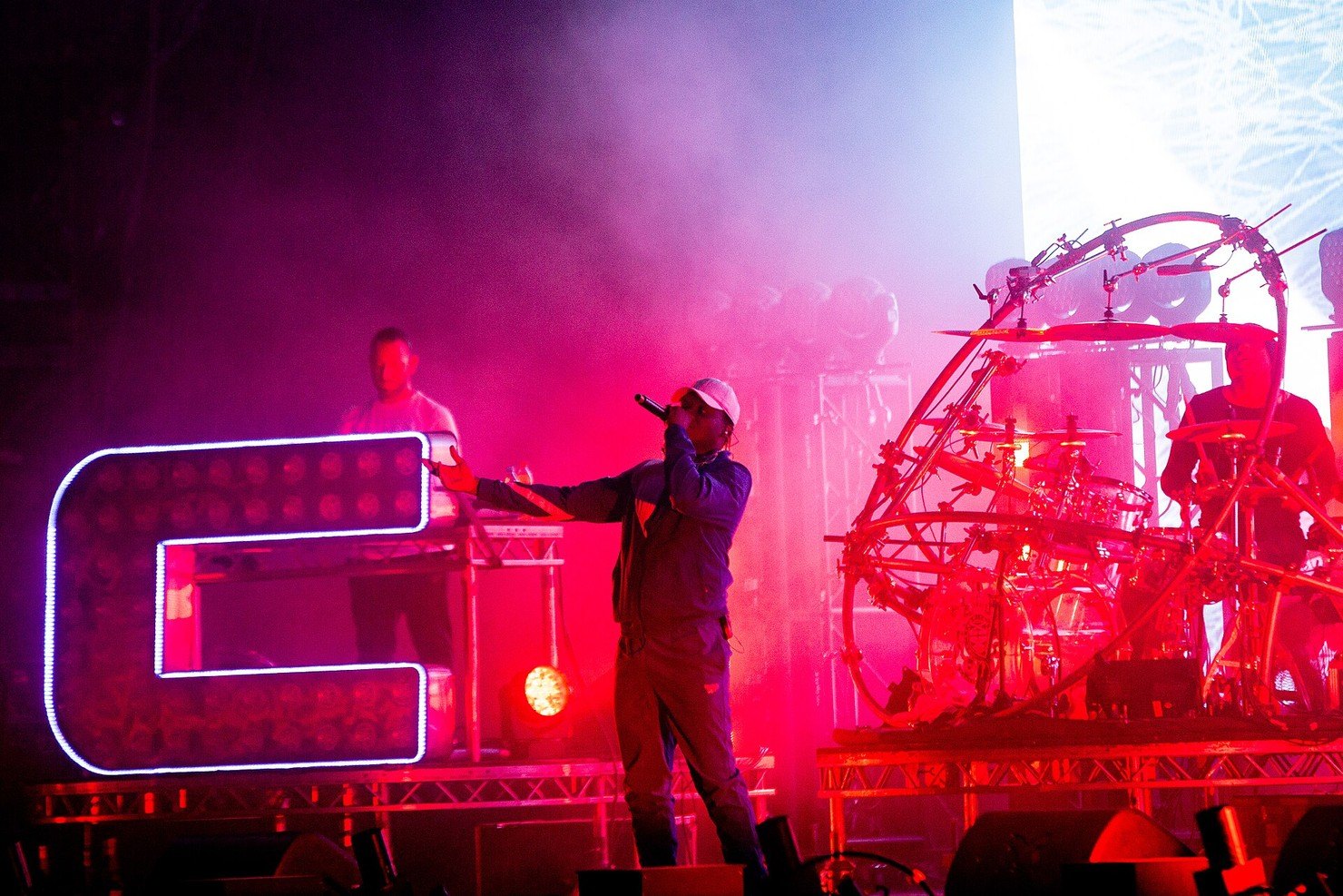Chase & Status live show on the SonneMondSterne main stage in 2018, a vocalist at the front in magenta light between a light-up letter C riser and a drummer in a circular kit