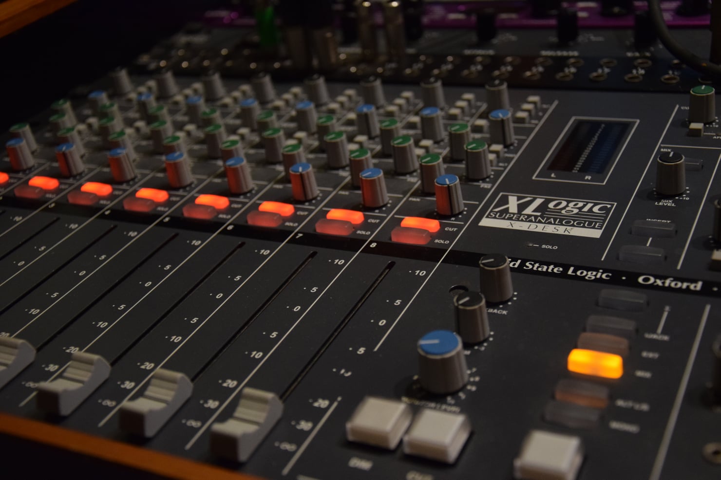 A Solid State Logic mixing desk in a studio, faders and rotaries in close focus