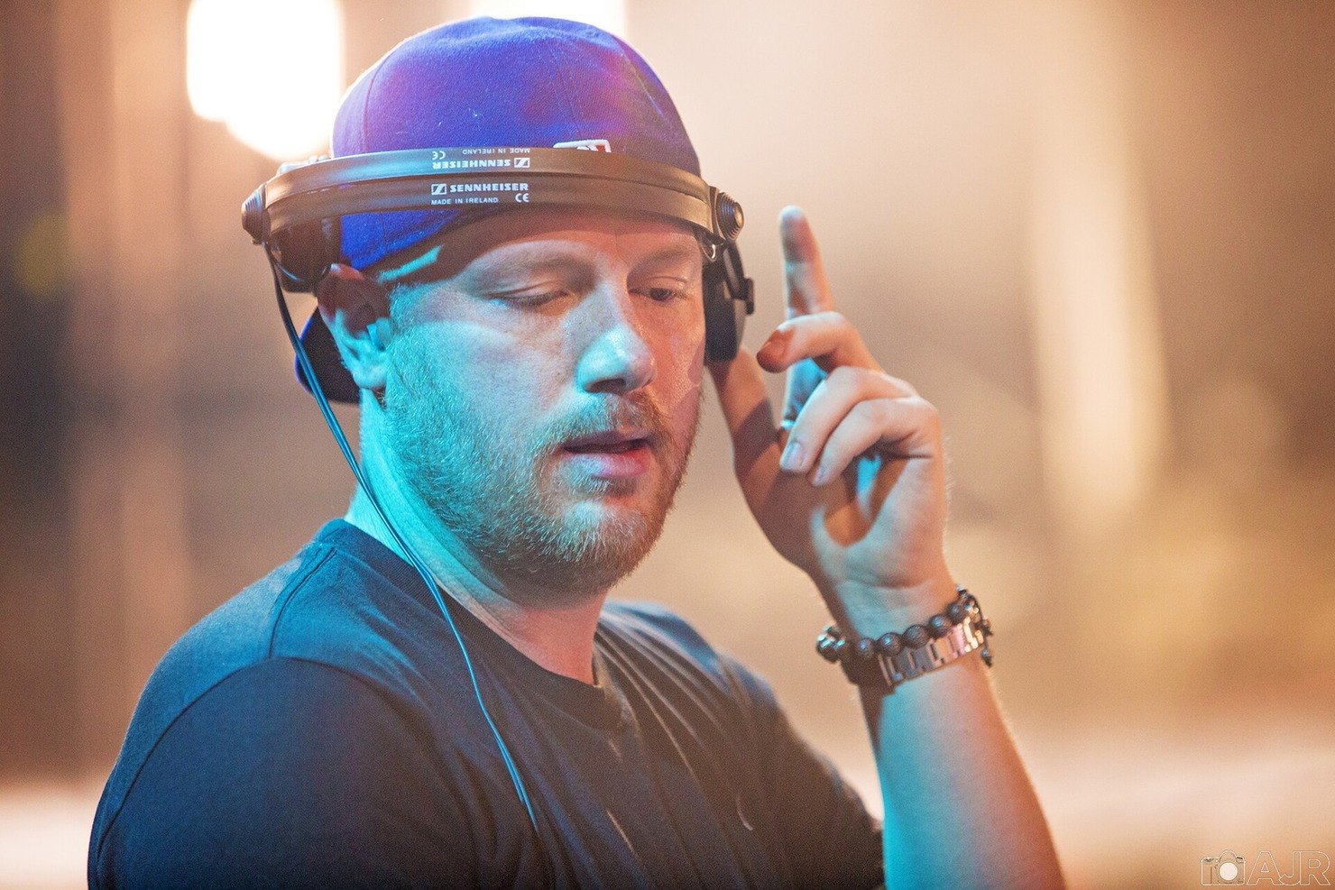 Eric Prydz in a backwards cap and headphones, one finger raised, DJing at EDC Las Vegas in 2014