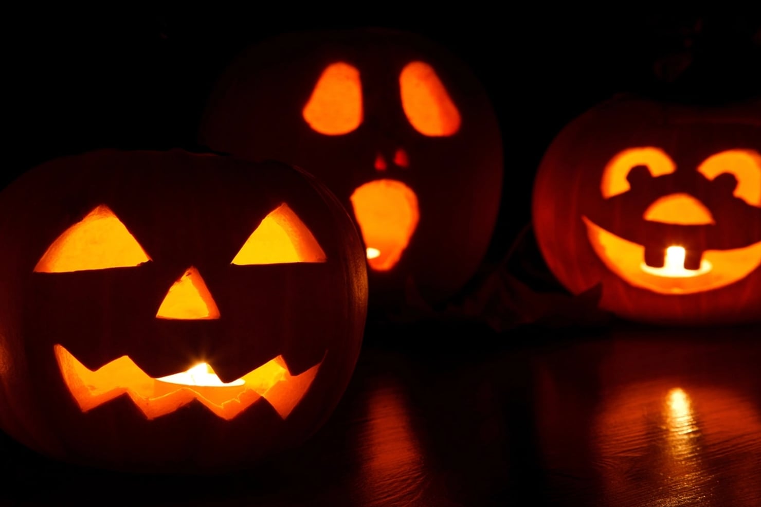Three carved jack-o-lanterns glowing in the dark