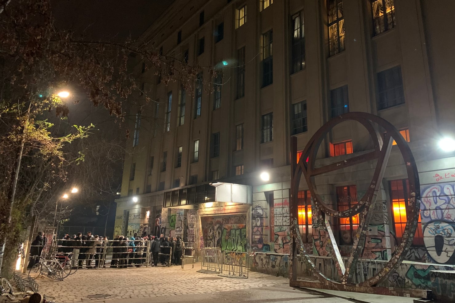 A queue of clubbers waiting outside a venue late at night under street lamps