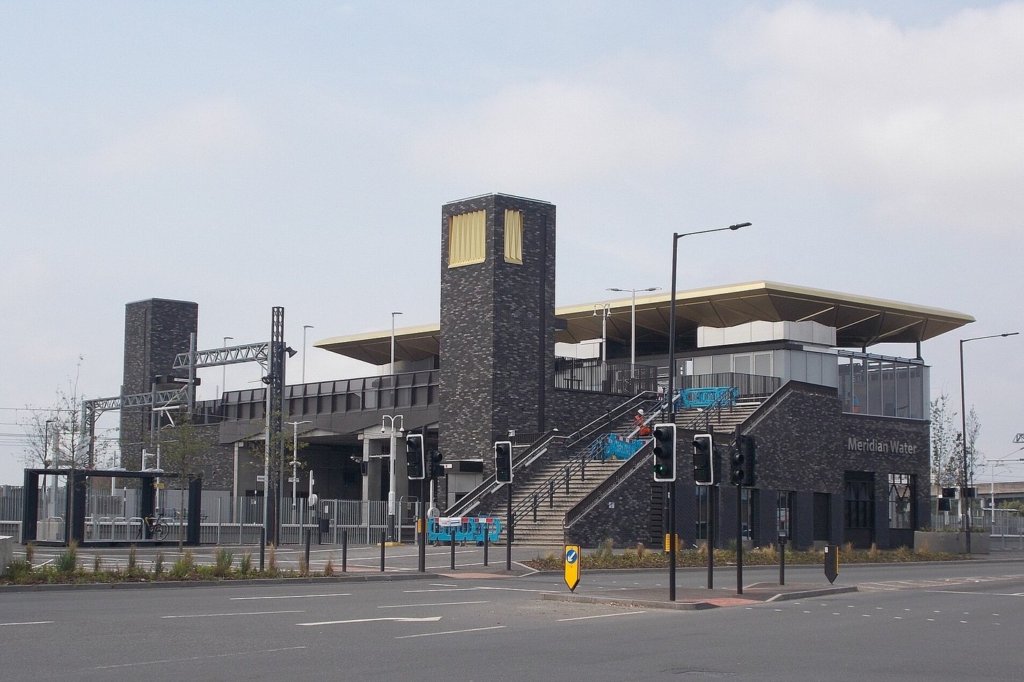 Meridian Water railway station in north London, its brick towers, stairs and canopy seen from the road, the closest station to Drumsheds