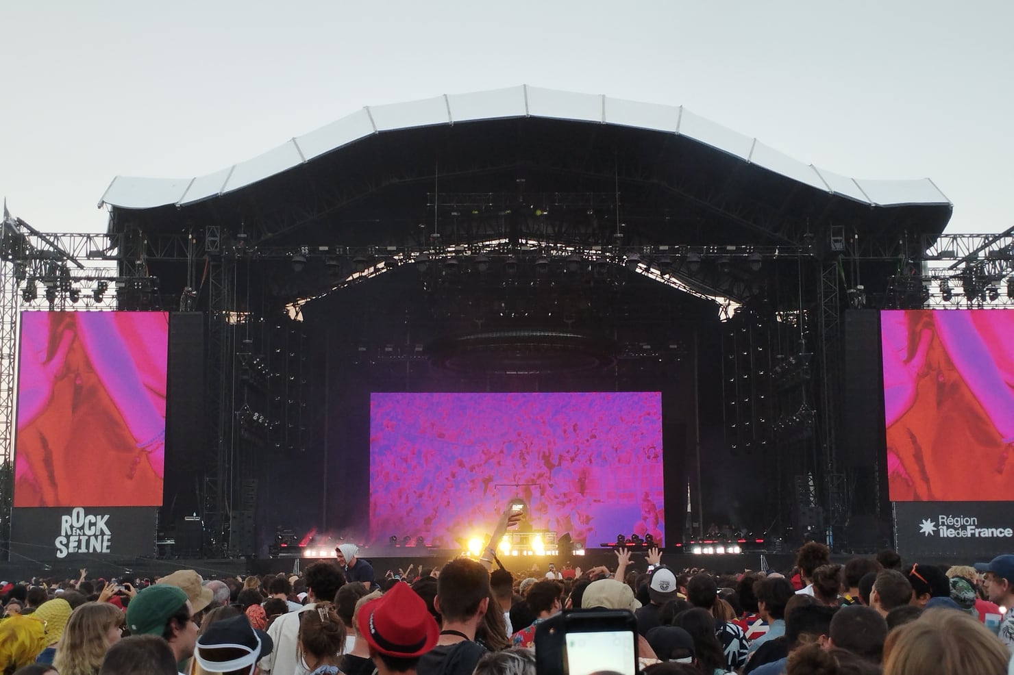 Jamie xx performing on a festival main stage washed in pink light