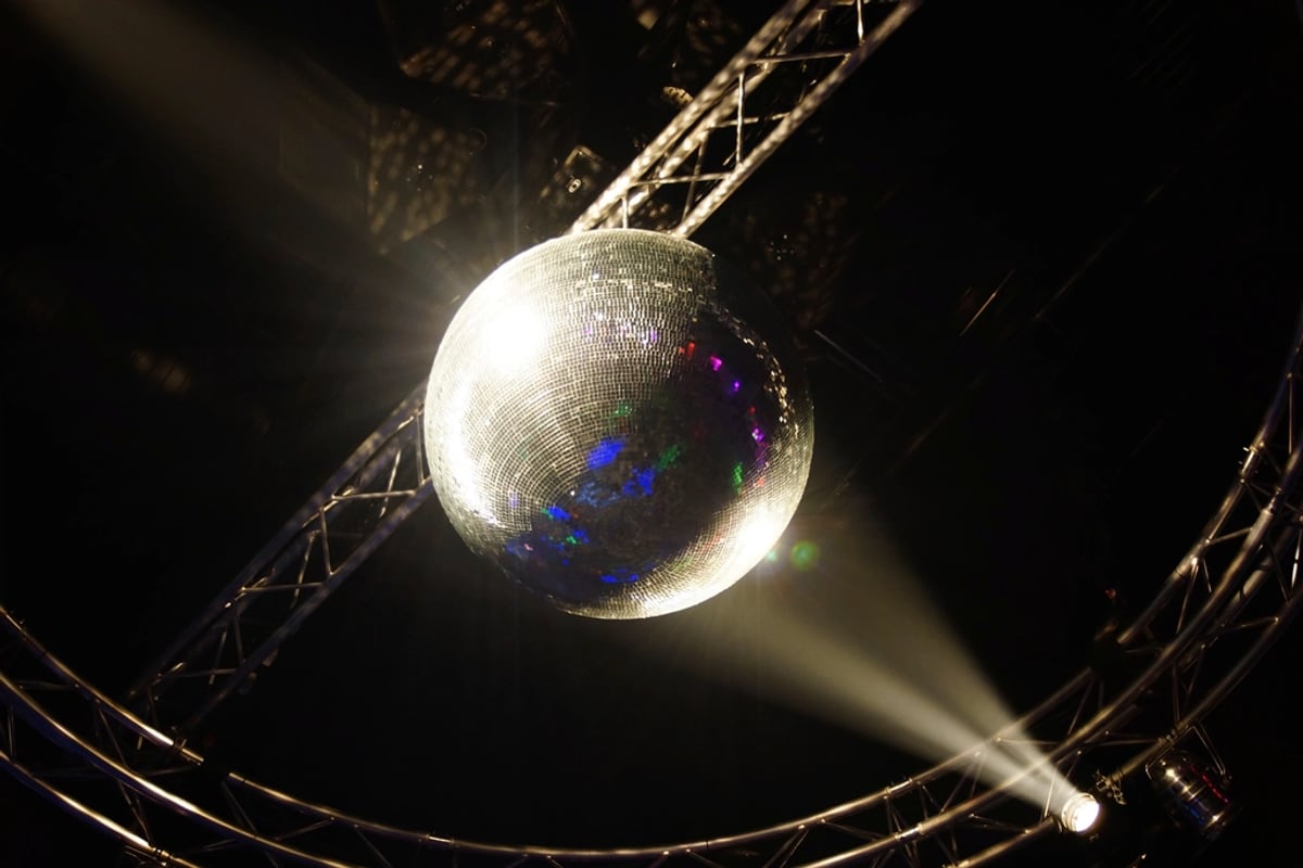 A mirror ball on a truss throwing light across a dark room