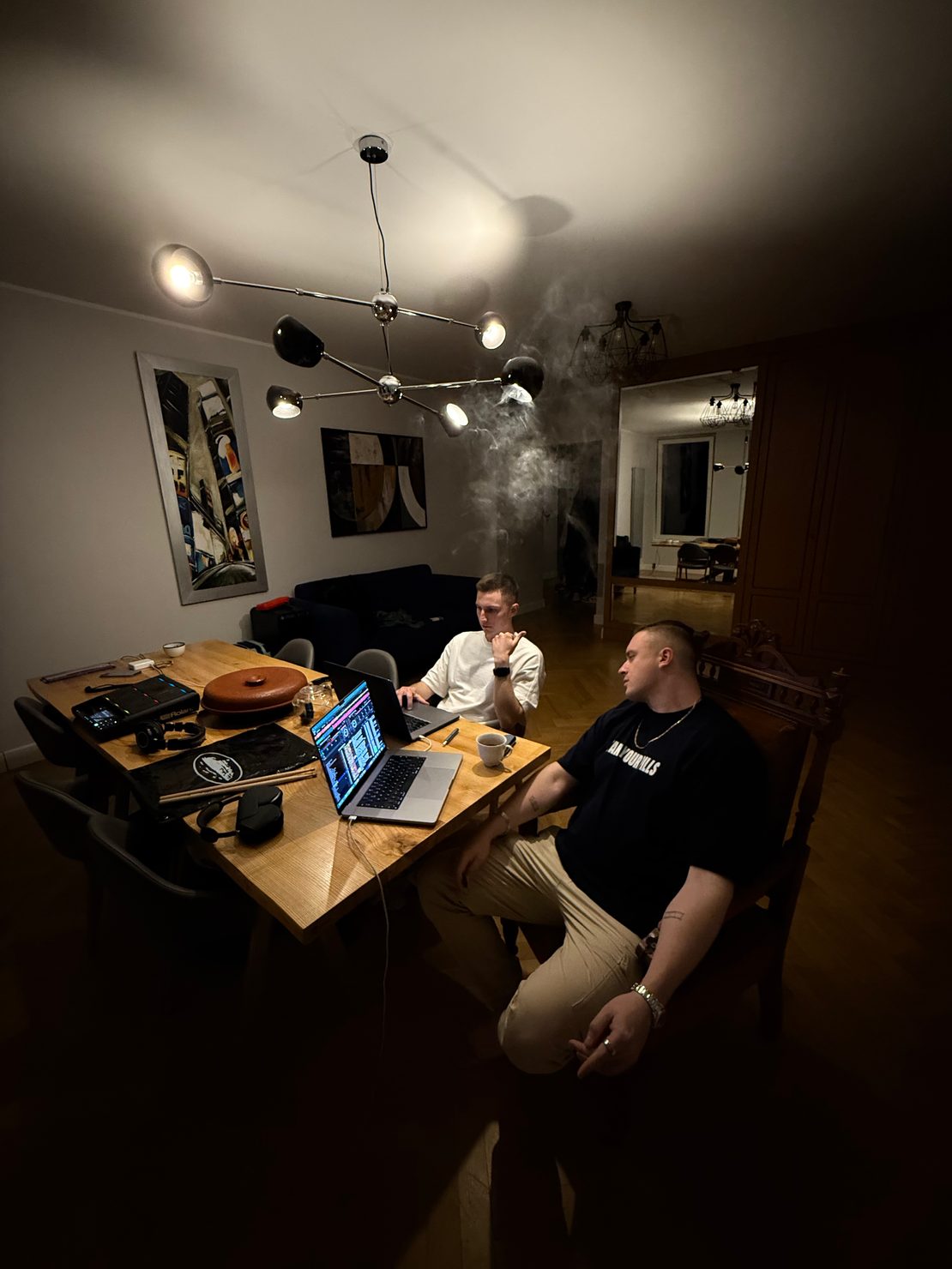 MNEEMO (Yaroslav Gorovoy) & Slavko sitting in a luxury apartment preparing for therapy performance. Laptop with rekordbox is open on a table. 