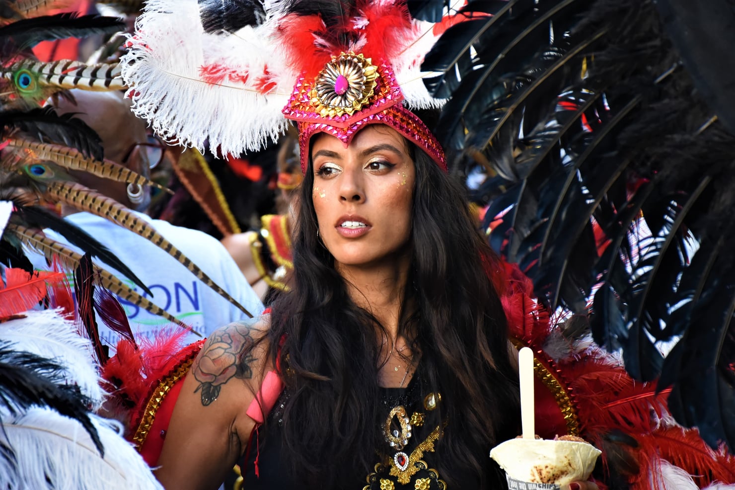 A masquerade performer in red feathered costume at Notting Hill Carnival