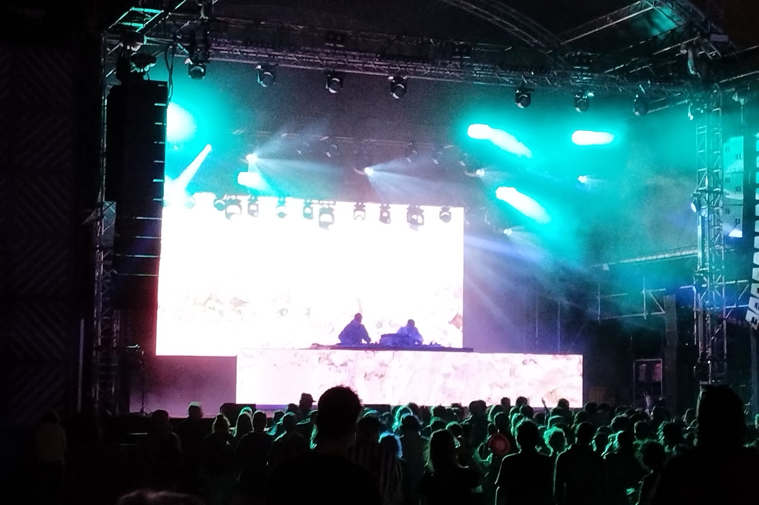Overmono performing live on stage under teal light