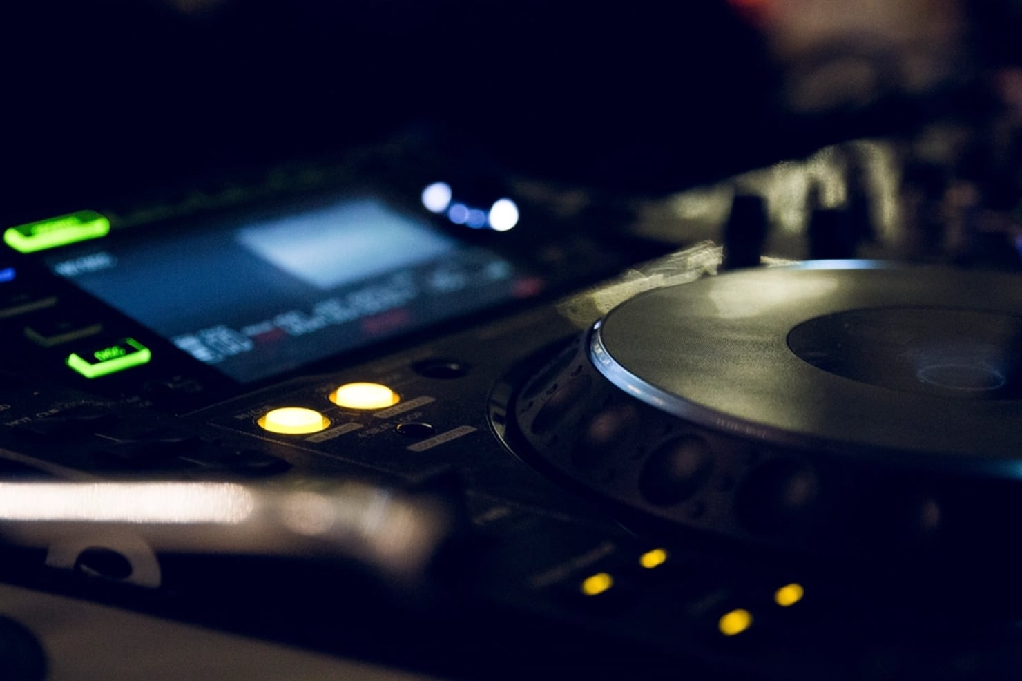 A CDJ lit by its own display in a dark booth