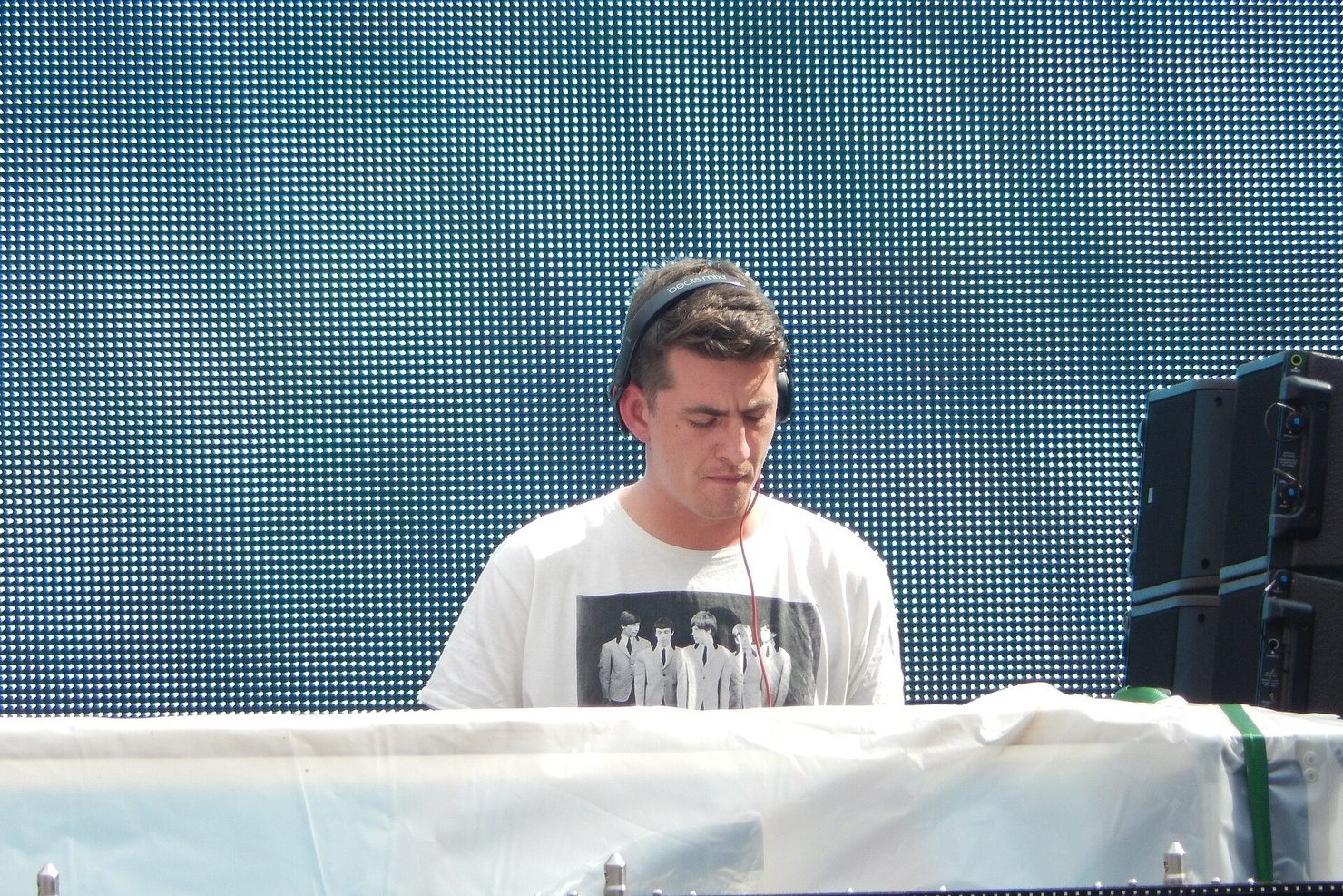 Skream in headphones and a Beatles T-shirt behind the decks in front of an LED wall at Spring Awakening, Chicago, 2015