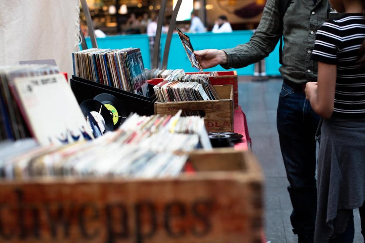 Crates of records at a vinyl market, a buyer flicking through