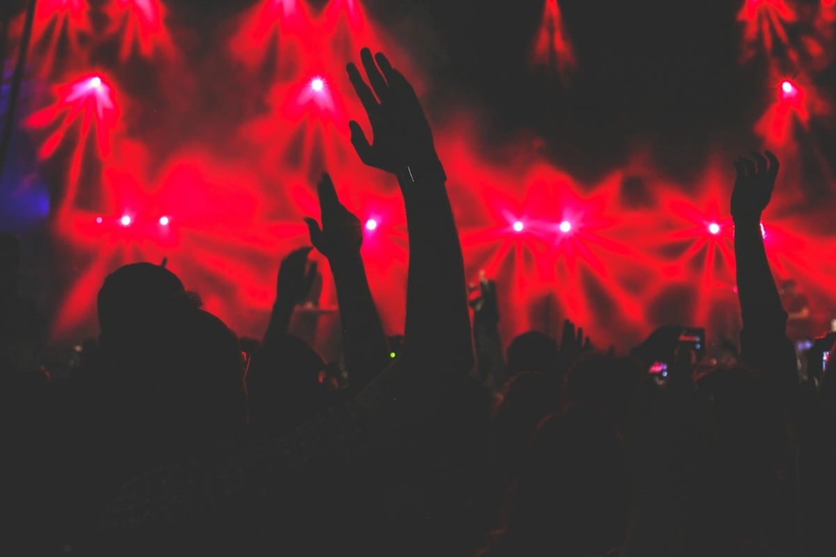 A rave crowd with hands up under red lasers